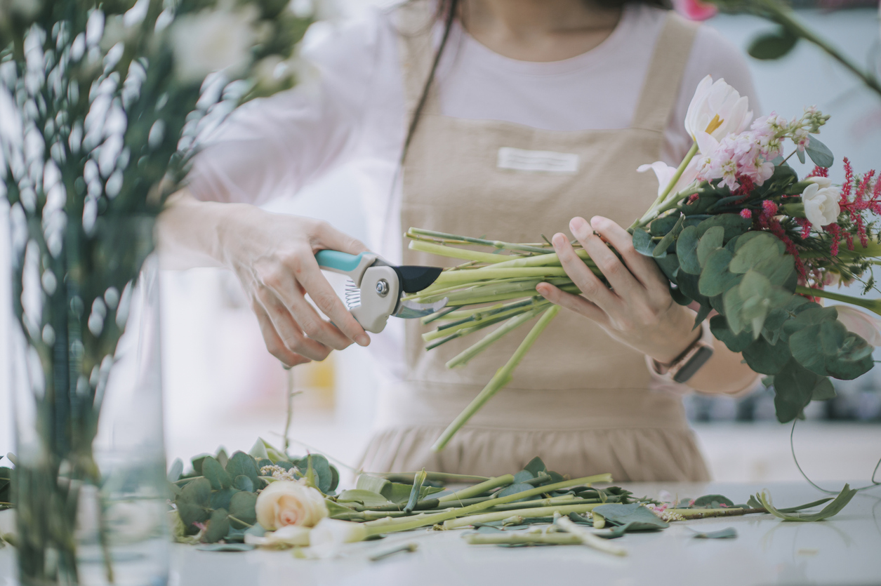 Close Up Asian Chinese Female Florist, Small Business Owner Cutting And Arranging Flowers Bouquet In Kitchen At Home . Daily Routine Of Running A Small Business Work From Home