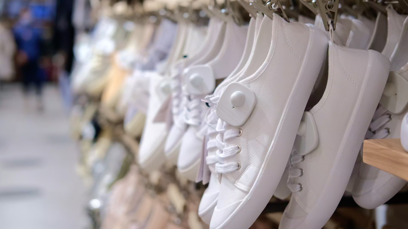 Many White Shoes Hanging In A Row In A Trendy Stylish Mass Market Store, Cheap Footwear Shopping On Sale. Shoe Shop With Simple Shoes For Everyday Use, White Sneakers In Different Sizes
