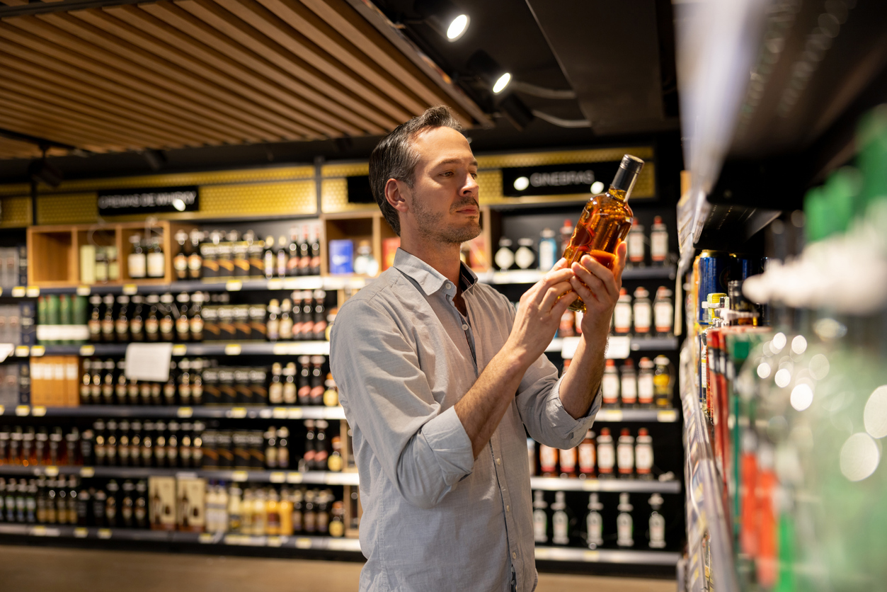 Man At The Supermarket Buying A Bottle Of Whiskey