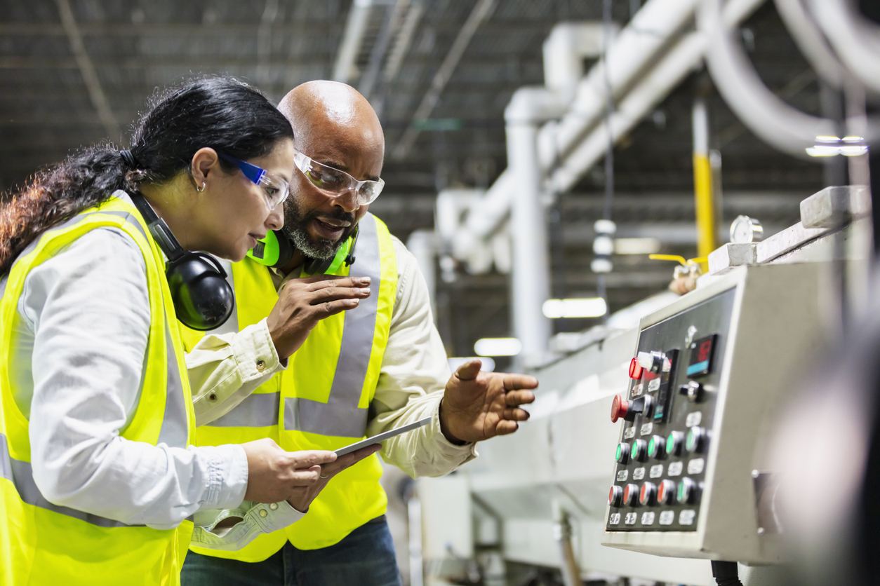 Multiracial Workers In Factory At Machine Control Panel
