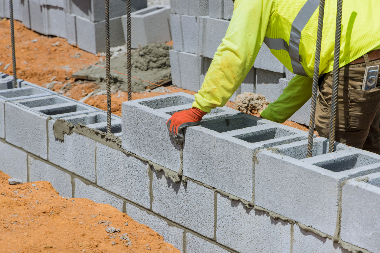 A Mason Is In The Process Of Mounting A Wall Of Aerated Concrete Blocks Using Masonry Techniques