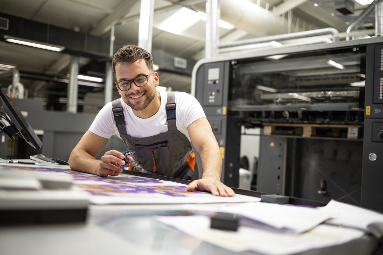 Print House Worker Controlling Printing Process Quality And Checking Colors With Magnifying Glass.